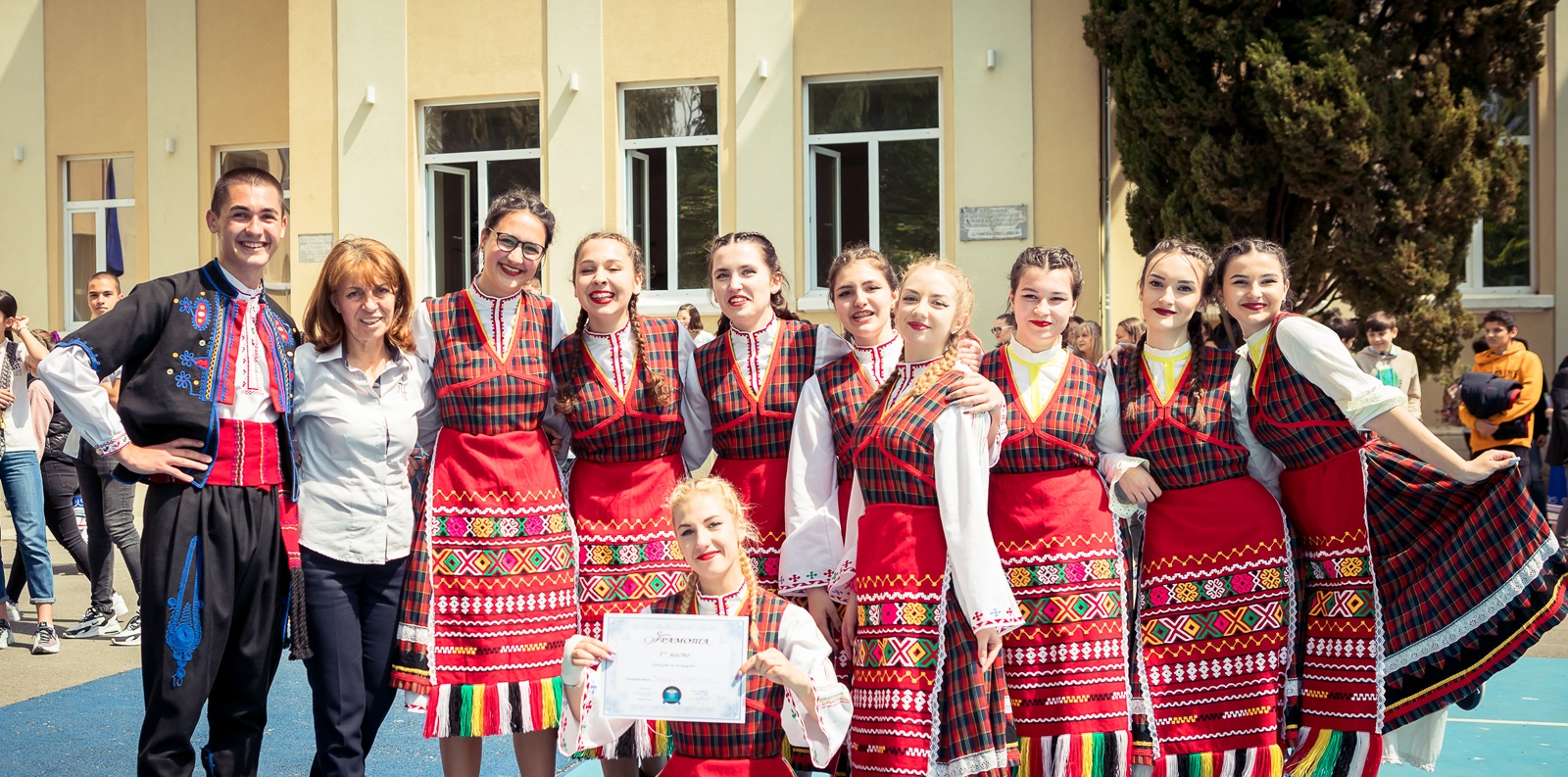 Ученици и преподавател в народни носии в двора на училището